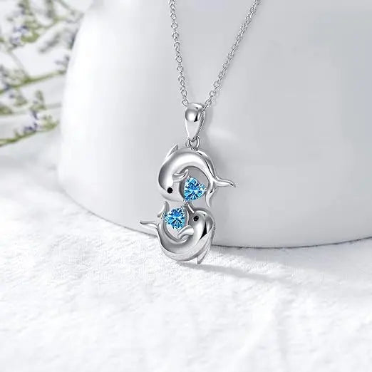 Collar plateado con dos delfines y cristal azul